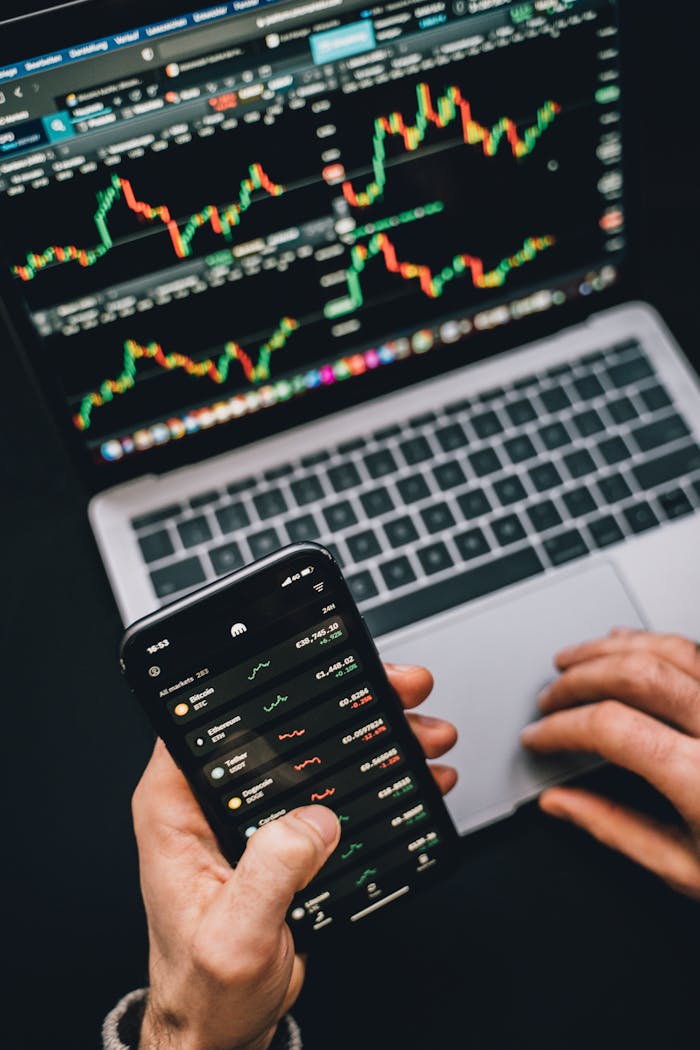 heros-img Person analyzing stock market data with a laptop and smartphone showing trading graphs.