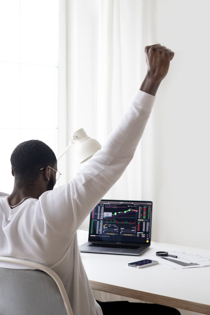services-01 A man celebrates a successful stock market trade while sitting at his desk.